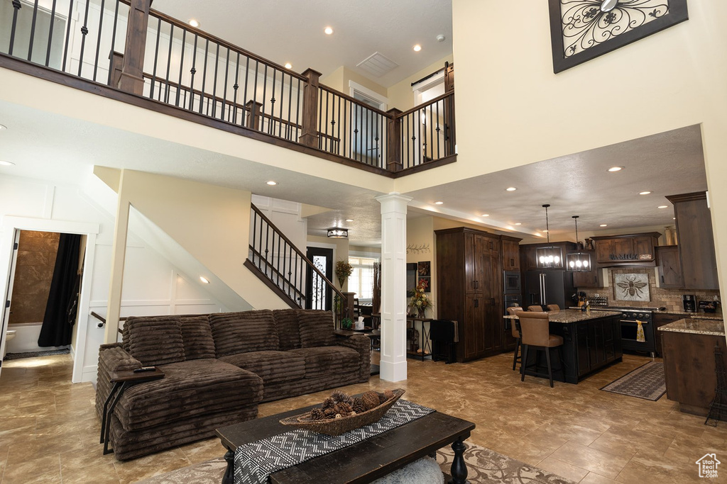 Living area with ornate columns, a towering ceiling, recessed lighting, and stairway