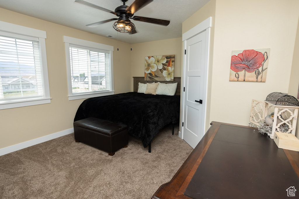Carpeted bedroom featuring baseboards and a ceiling fan