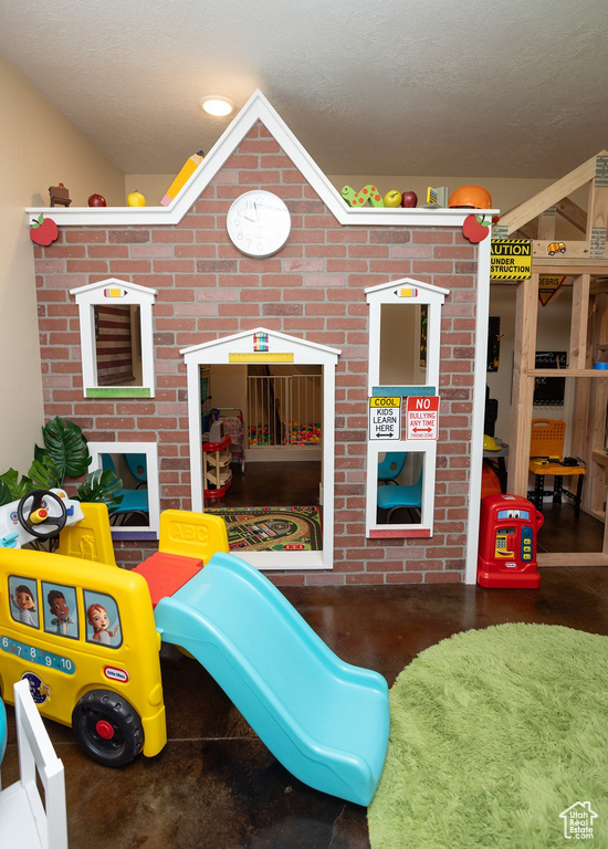 Playroom featuring finished concrete flooring, a textured ceiling, and vaulted ceiling