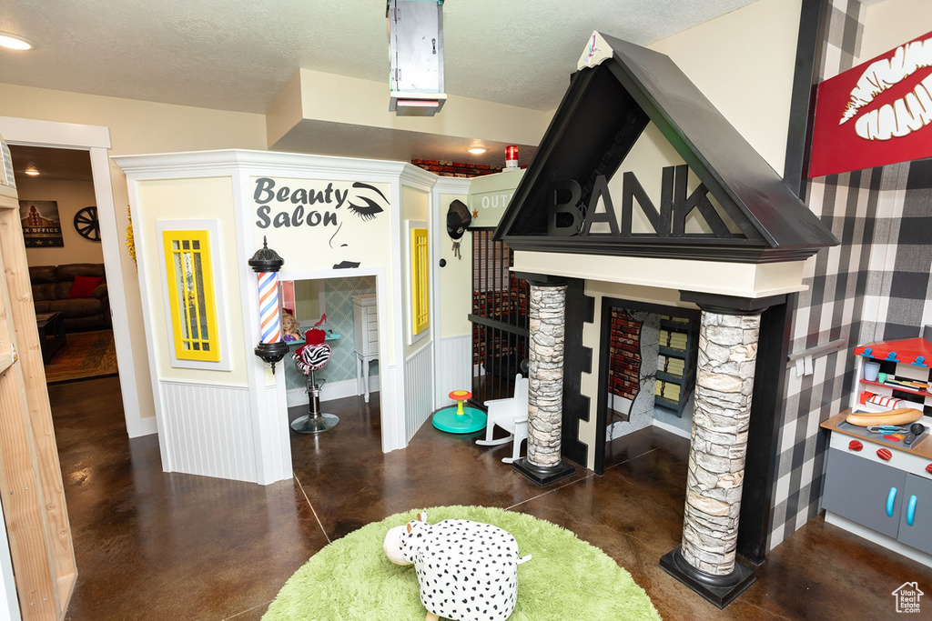 Misc room with finished concrete floors, a wainscoted wall, and a textured ceiling
