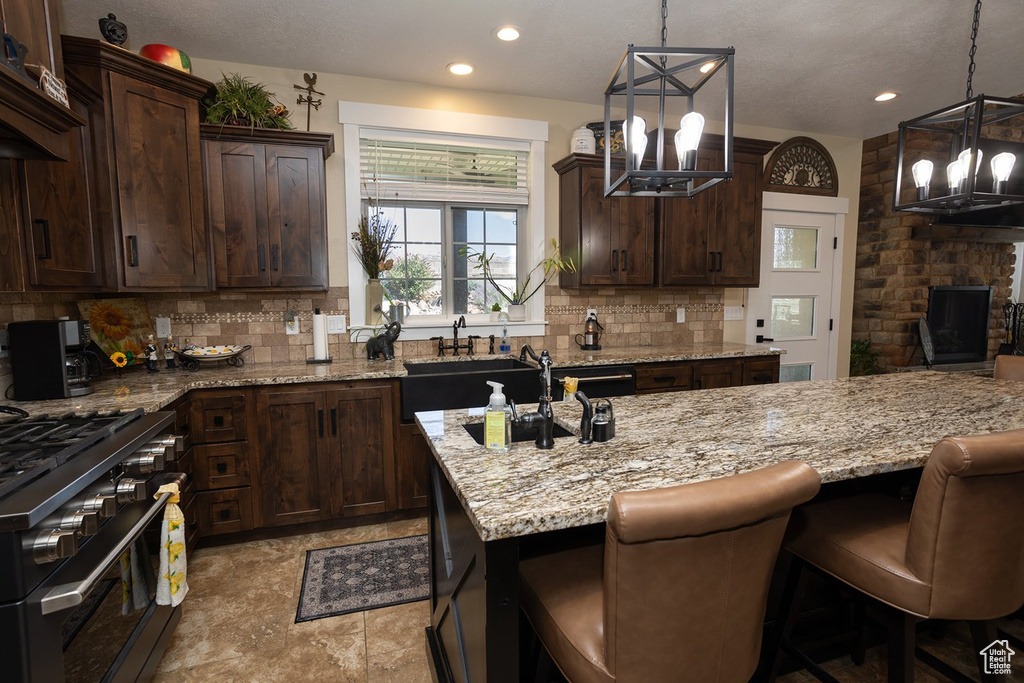 Kitchen featuring a chandelier, gas stove, tasteful backsplash, light stone countertops, and recessed lighting