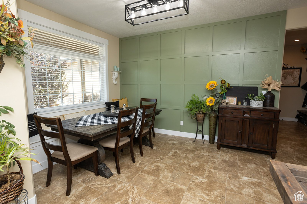 Dining space with a decorative wall and light stone finish flooring