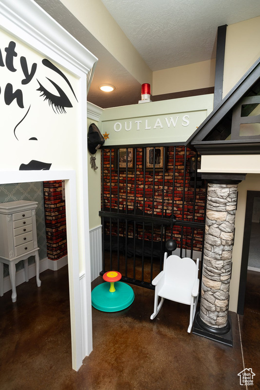 Recreation room with concrete flooring and a textured ceiling
