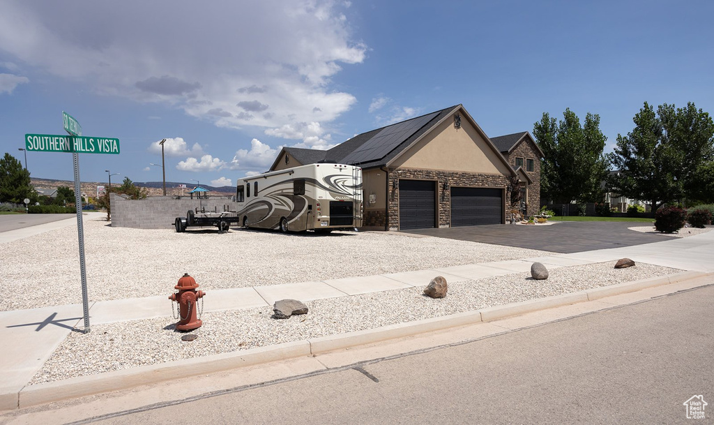 View of front of property featuring stone siding, a garage, driveway, and stucco siding