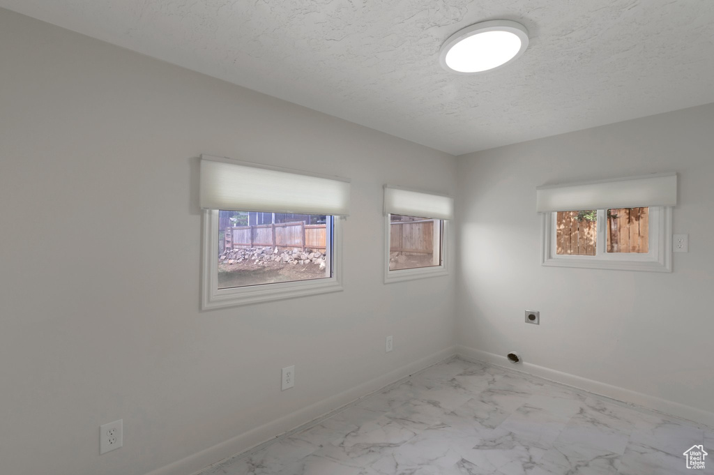 Spare room featuring light marble finish flooring and a textured ceiling