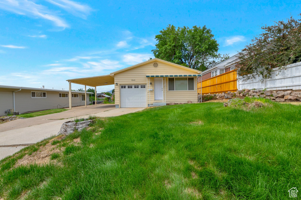 View of front of home featuring driveway, a carport, and a garage
