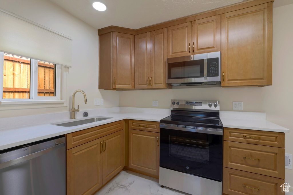 Kitchen with appliances with stainless steel finishes, light marble finish flooring, and light countertops