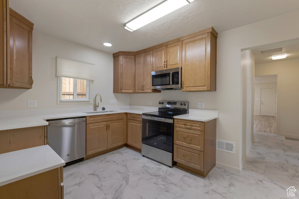 Kitchen with stainless steel appliances, light marble finish flooring, and light countertops