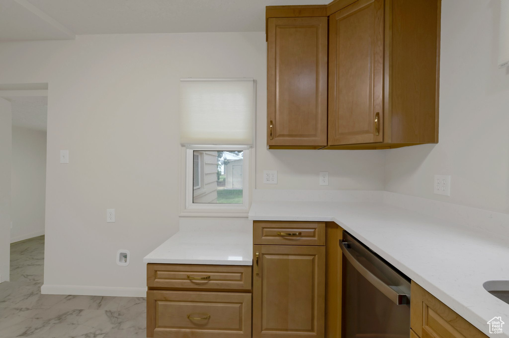 Kitchen featuring dishwasher, light marble finish floors, light countertops, and brown cabinets