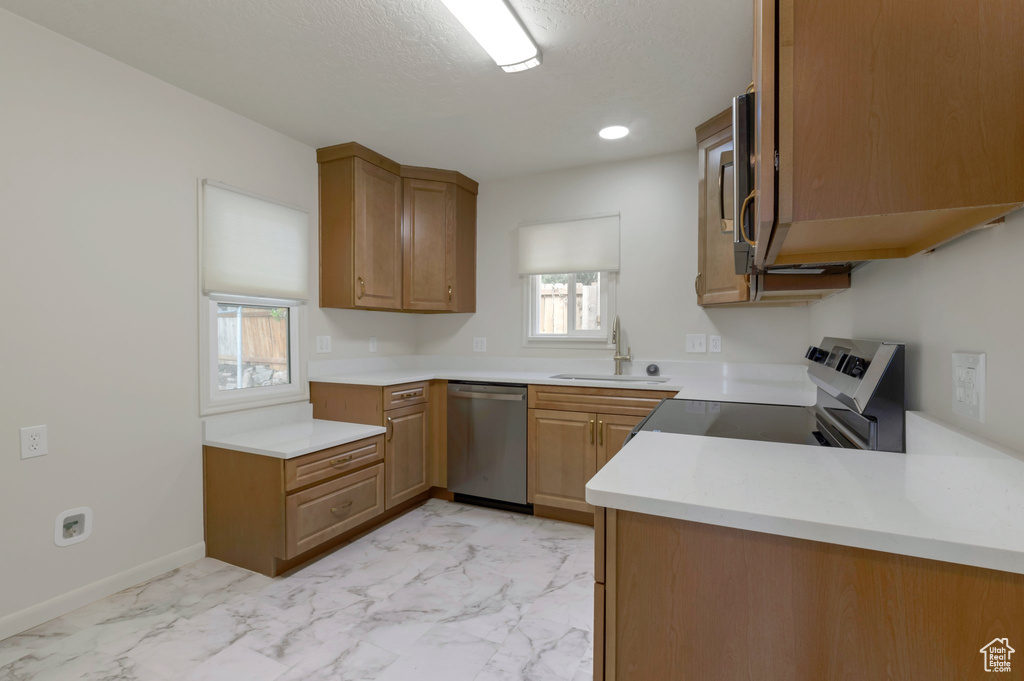 Kitchen featuring dishwasher, light marble finish floors, light countertops, white electric stove, and a textured ceiling