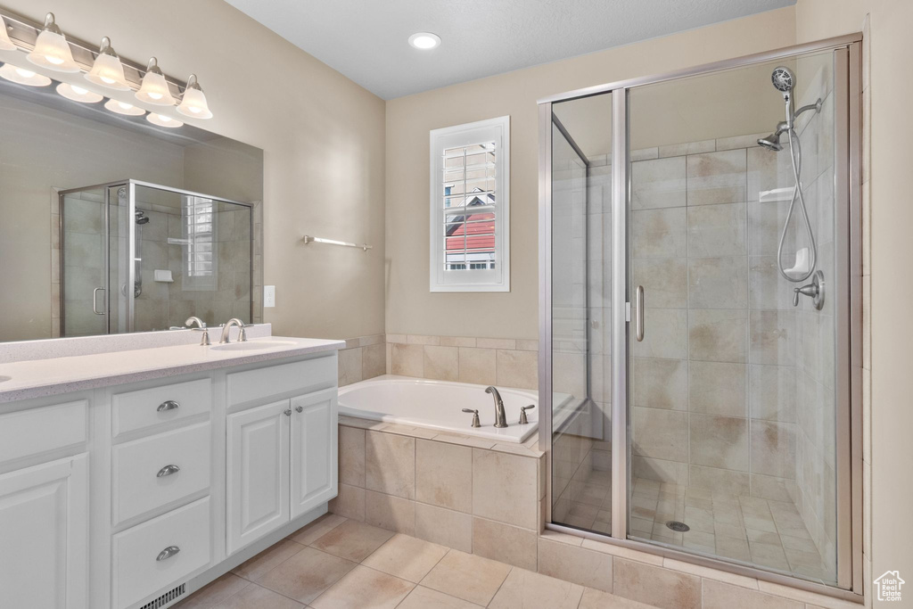 Bathroom with double vanity, a shower stall, a garden tub, tile patterned floors, and recessed lighting