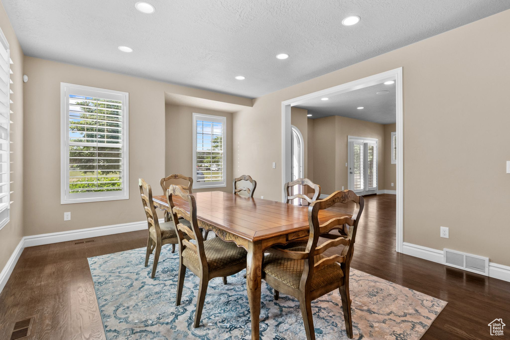 Dining space with wood finished floors, recessed lighting, and a textured ceiling