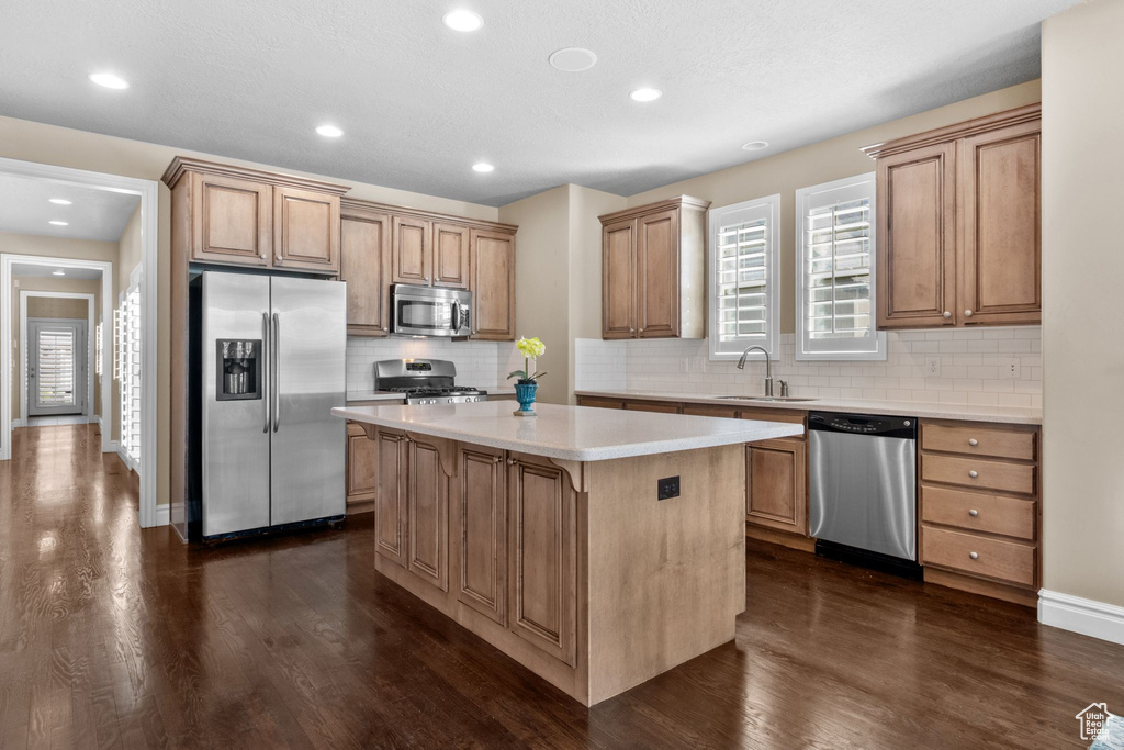 Kitchen featuring stainless steel appliances, a center island, dark wood finished floors, tasteful backsplash, and recessed lighting