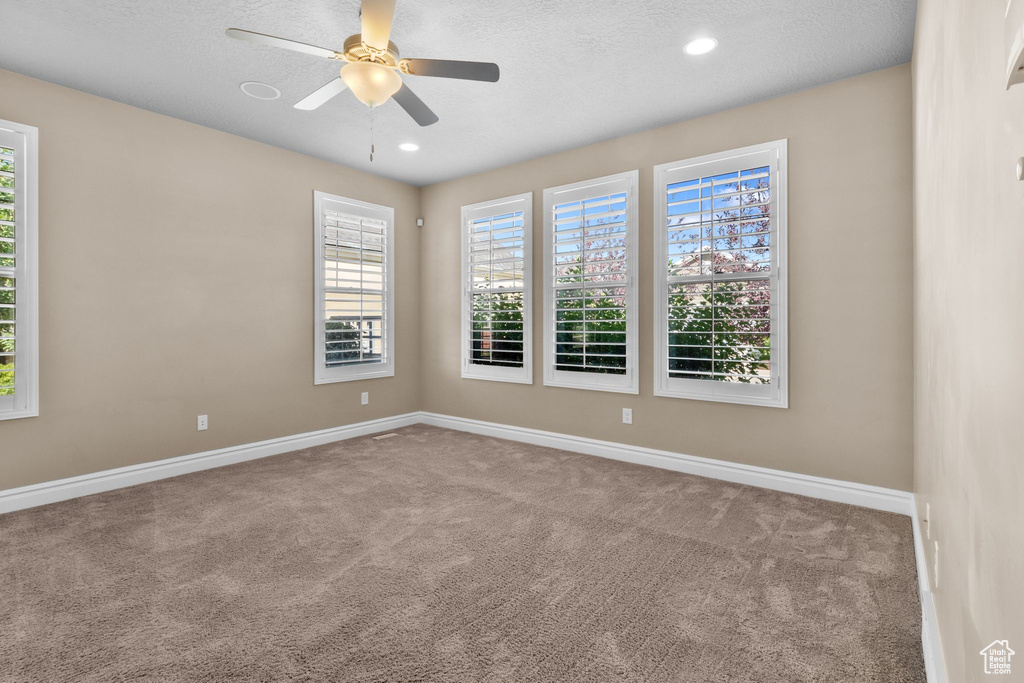 Unfurnished room featuring carpet floors, healthy amount of natural light, ceiling fan, recessed lighting, and a textured ceiling