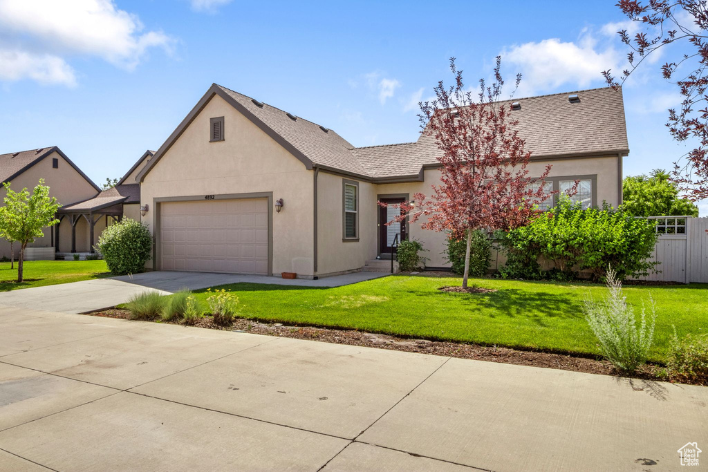 View of front of property featuring an attached garage, driveway, stucco siding, and a shingled roof