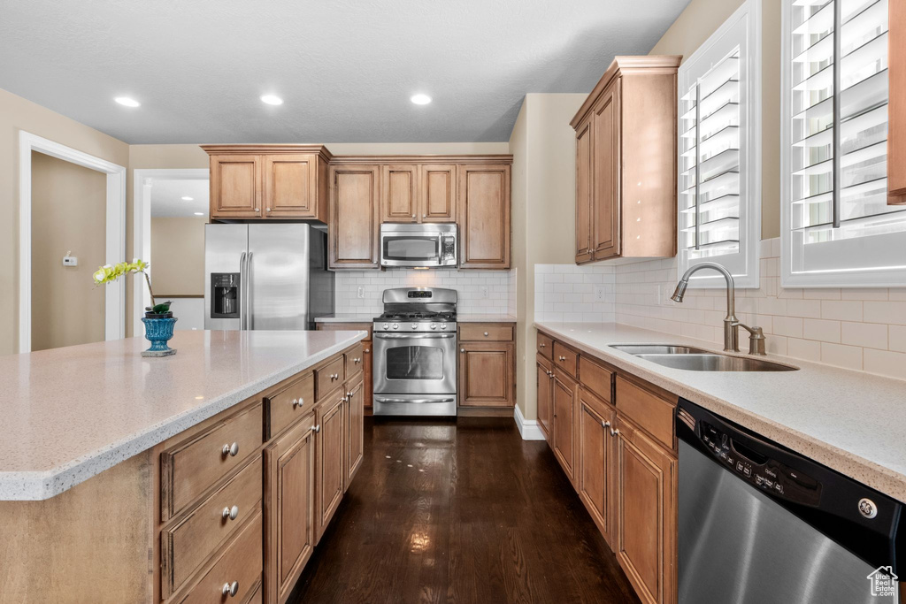 Kitchen with stainless steel appliances, decorative backsplash, dark wood finished floors, light stone counters, and recessed lighting