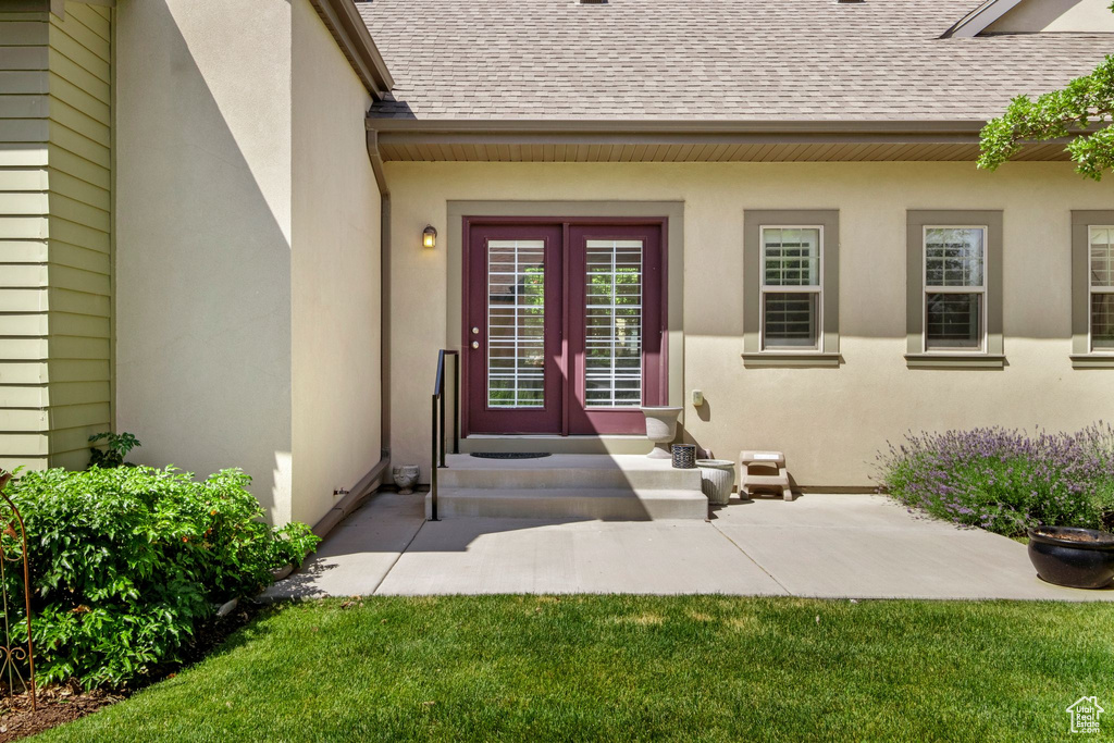 View of exterior entry with a shingled roof, french doors, and stucco siding