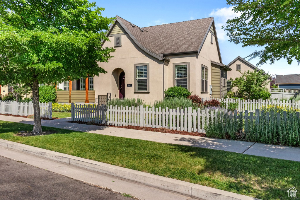 View of front of property with stucco siding, a shingled roof, and a fenced front yard