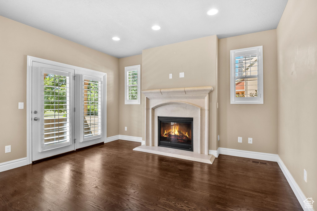 Unfurnished living room with wood finished floors, a fireplace, plenty of natural light, and recessed lighting