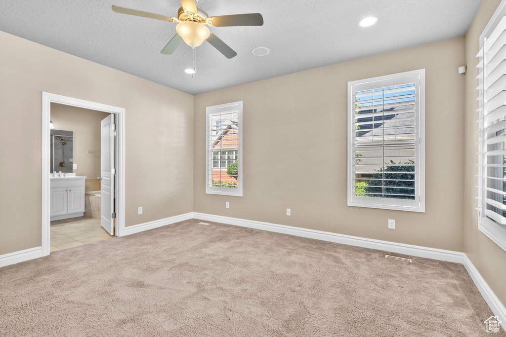 Unfurnished bedroom featuring light colored carpet, a ceiling fan, ensuite bathroom, and recessed lighting
