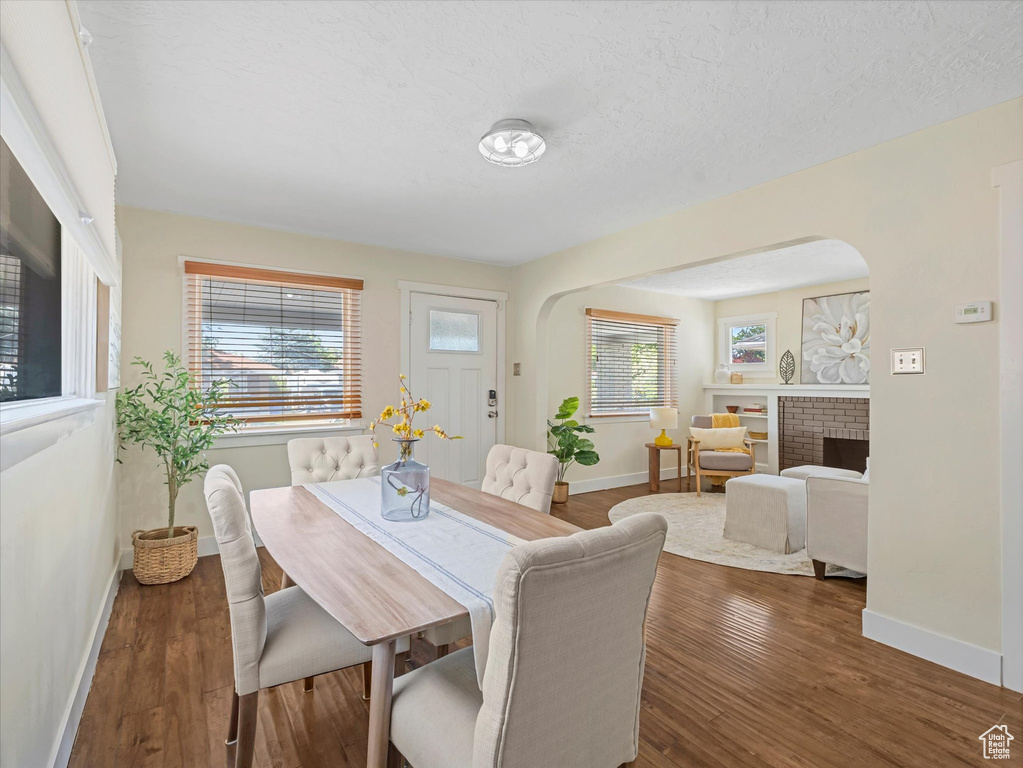 Dining area with arched walkways, plenty of natural light, and wood finished floors