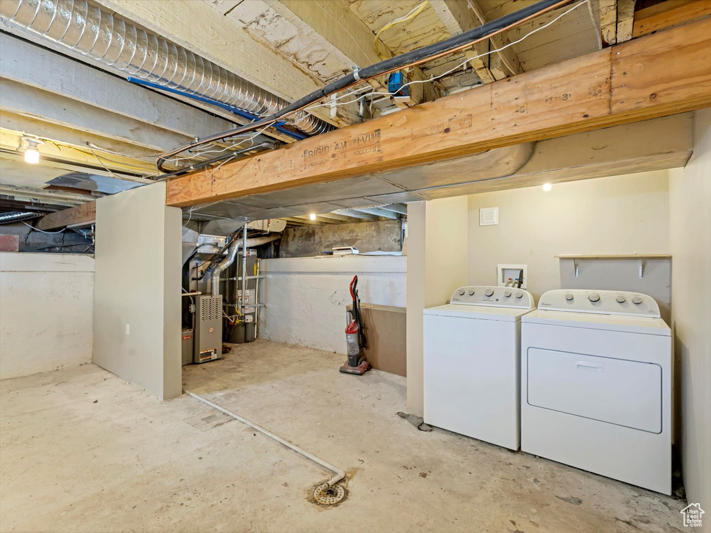 Unfinished basement with washing machine and dryer, heating unit, and strapped water heater