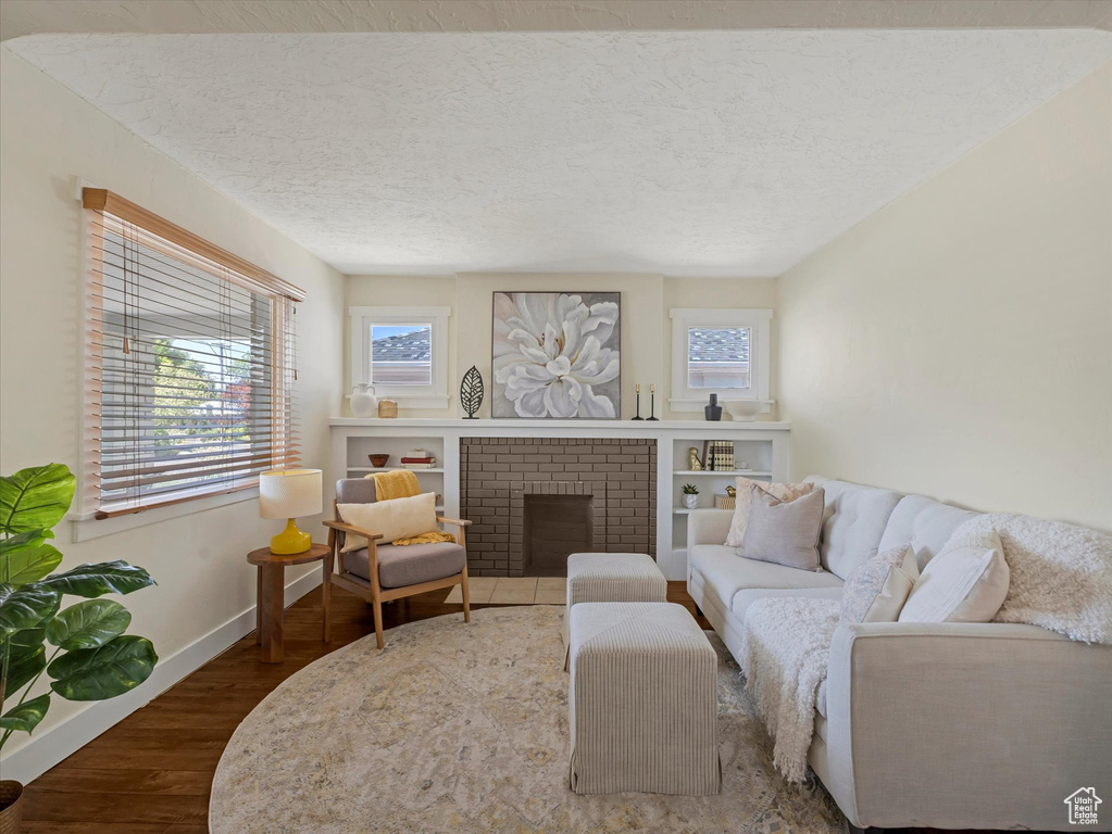 Living room featuring wood finished floors, a textured ceiling, and a fireplace
