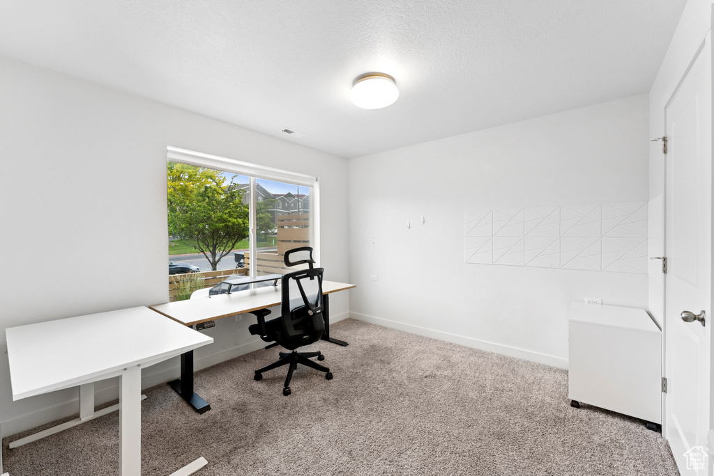 Carpeted home office featuring baseboards