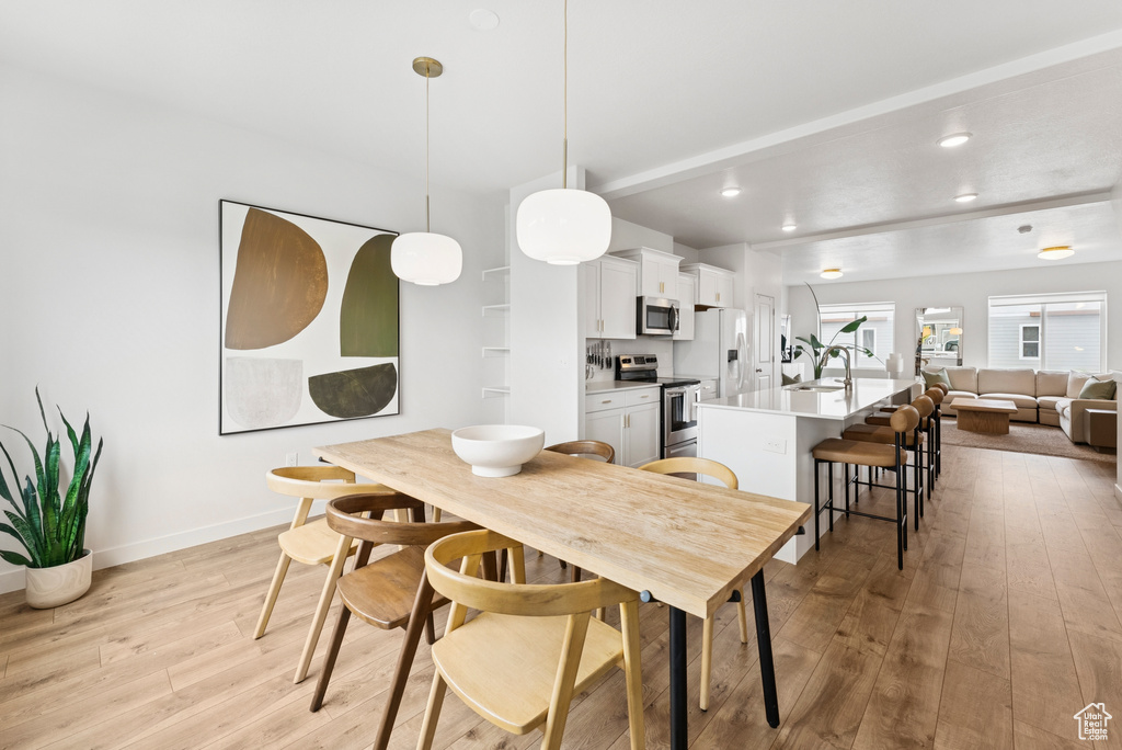 Dining area featuring light wood-style flooring, recessed lighting, and beam ceiling