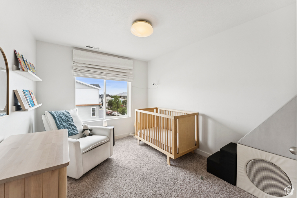 Carpeted bedroom featuring baseboards and a nursery area