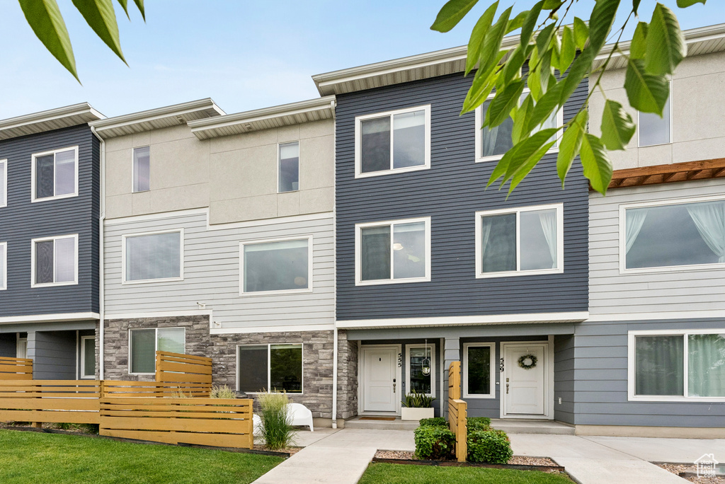 Townhome / multi-family property featuring a front lawn and stone siding