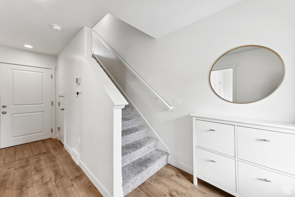 Stairway featuring wood finished floors and recessed lighting