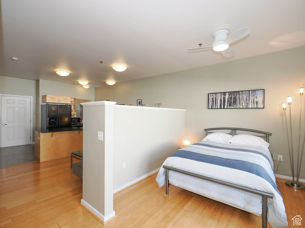Bedroom featuring black fridge, light wood finished floors, and baseboards