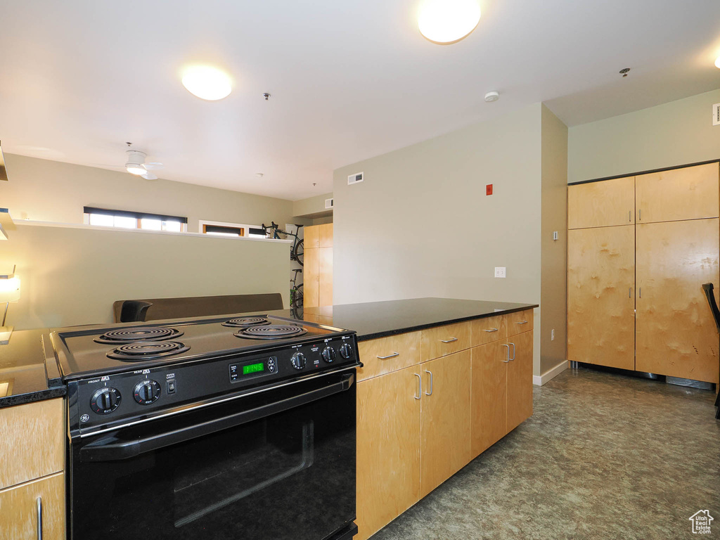 Kitchen featuring electric range, dark countertops, and light brown cabinets