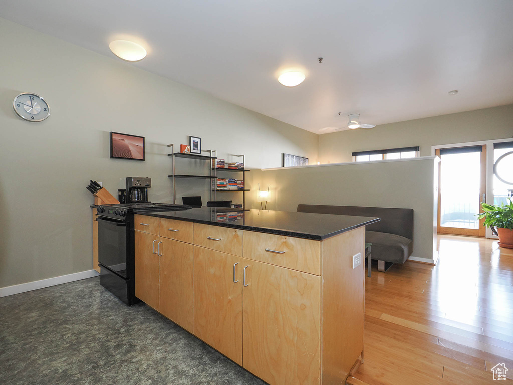 Kitchen featuring black range, baseboards, dark countertops, light brown cabinets, and a peninsula