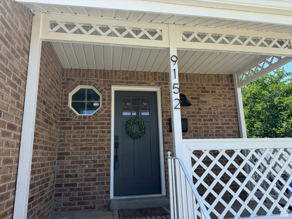 Entrance to property featuring brick siding and covered porch