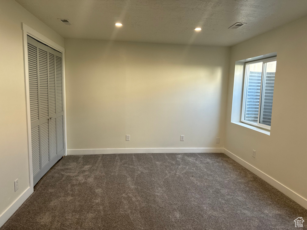 Unfurnished bedroom featuring dark carpet, a closet, and recessed lighting