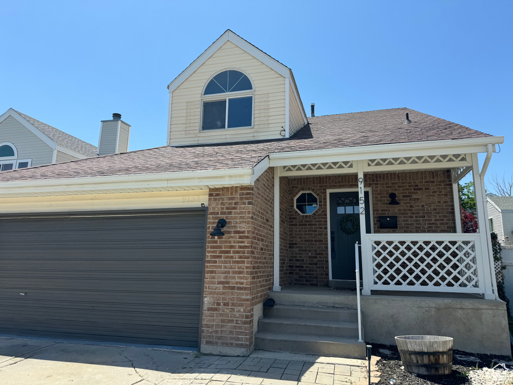 View of front of property with brick siding, roof with shingles, and a porch