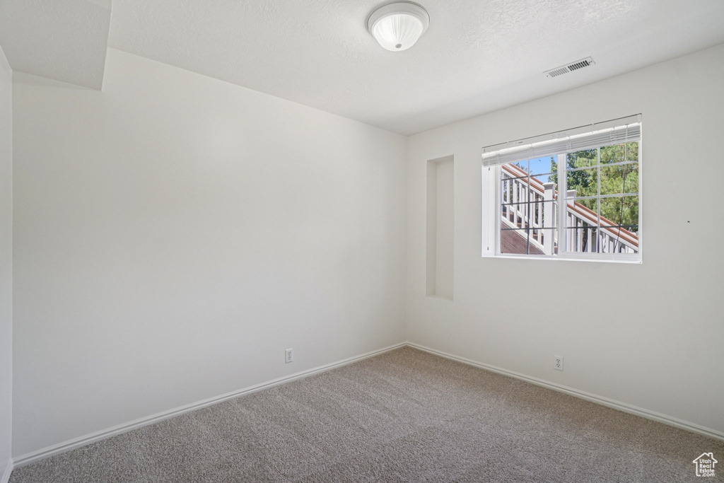 Carpeted spare room featuring baseboards