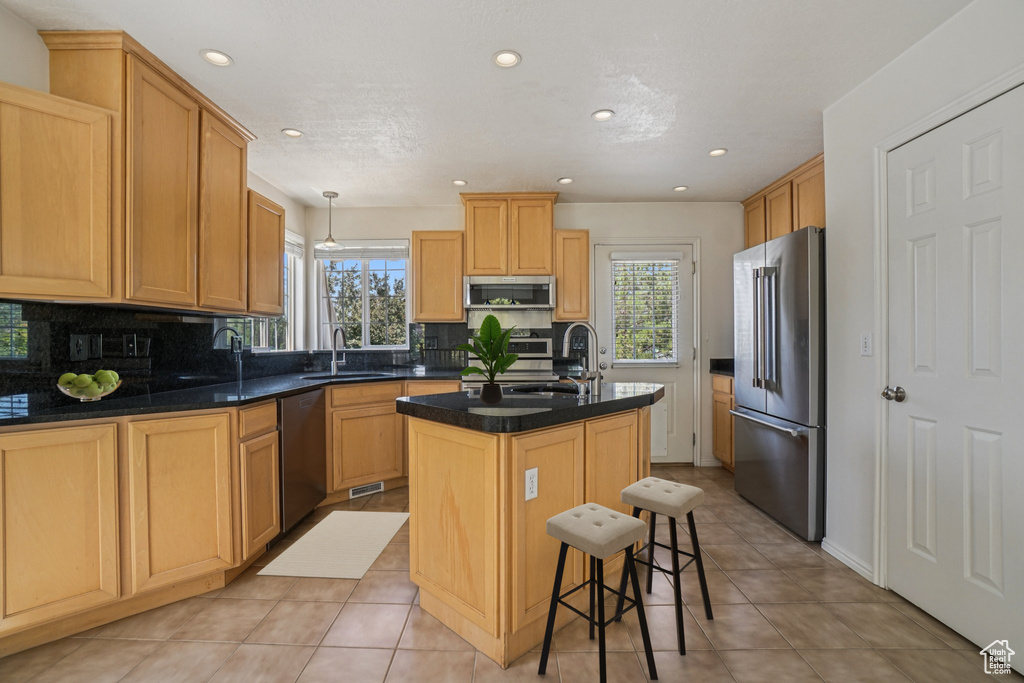Kitchen with appliances with stainless steel finishes, plenty of natural light, decorative backsplash, an island with sink, and recessed lighting