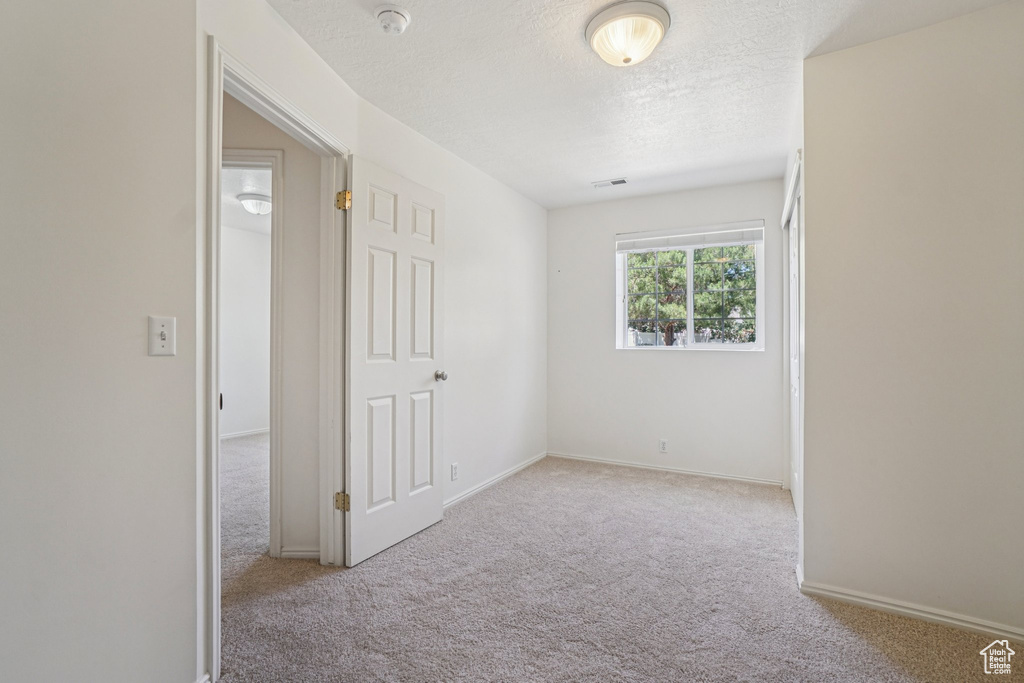 Carpeted spare room featuring a smoke detector and a textured ceiling