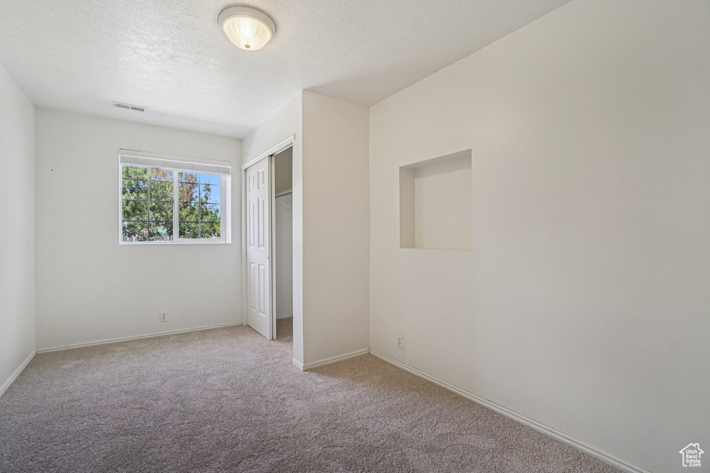 Unfurnished bedroom featuring carpet floors, a closet, and a textured ceiling