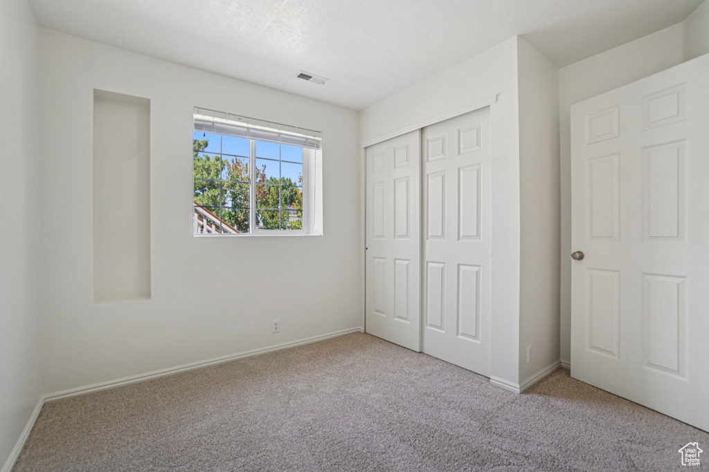 Unfurnished bedroom with carpet and a closet