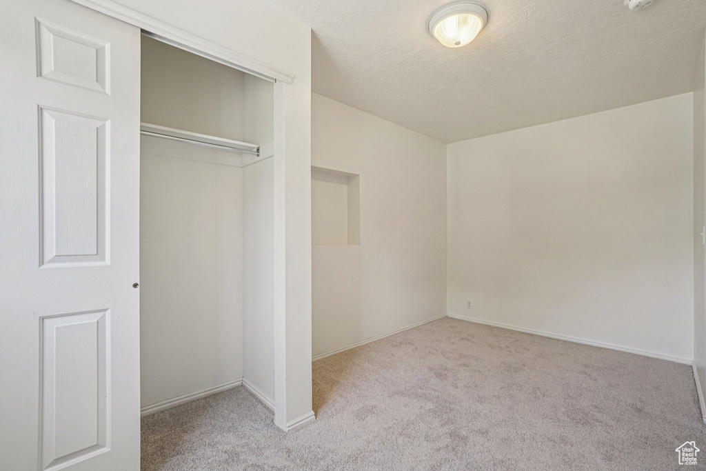 Unfurnished bedroom featuring carpet floors, a closet, and a textured ceiling