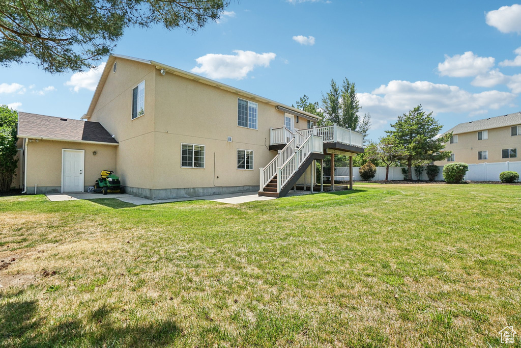 Back of property with stairs, a wooden deck, a patio, and stucco siding
