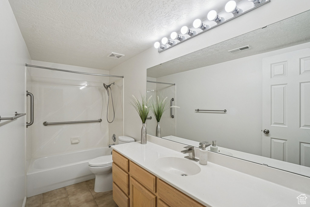 Full bath with a textured ceiling, bathtub / shower combination, vanity, and tile patterned flooring