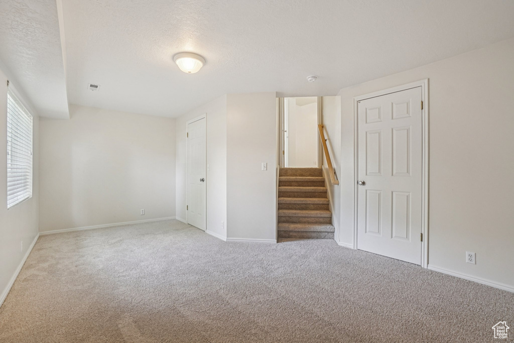 Spare room featuring carpet floors, stairway, and a textured ceiling