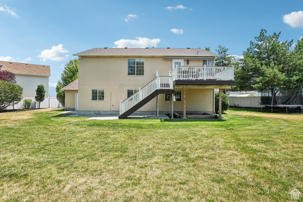 Back of house featuring a trampoline, stairs, a deck, stucco siding, and a patio area