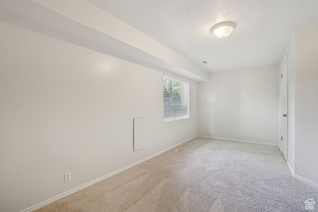 Carpeted empty room featuring baseboards and a textured ceiling