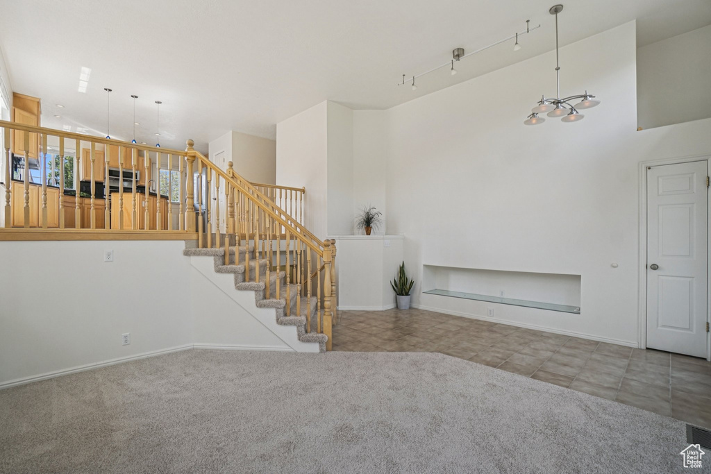 Stairway with tile patterned floors, a high ceiling, carpet flooring, and a chandelier